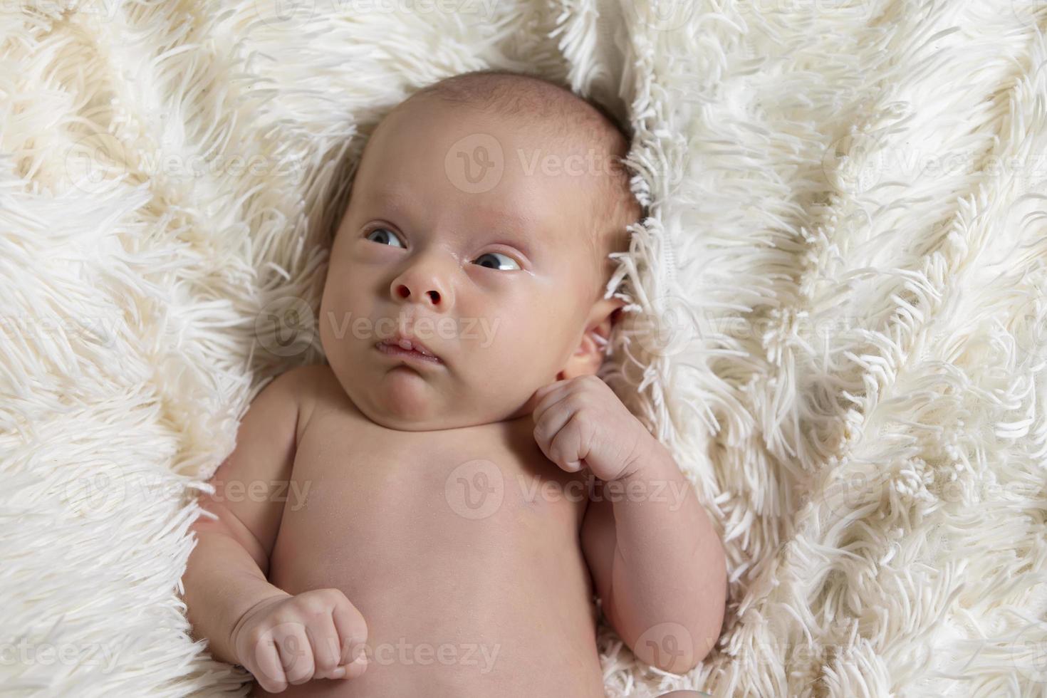 Newborn baby with a funny face. Little baby on a fur bed. photo