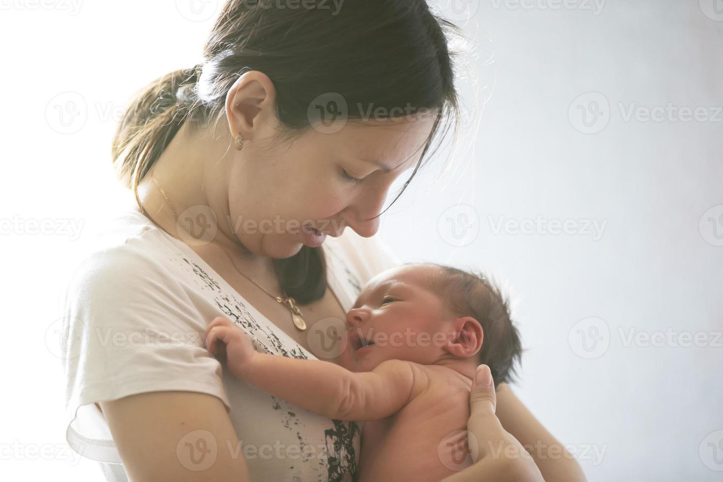 A young mother holds a newborn baby in her arms. photo