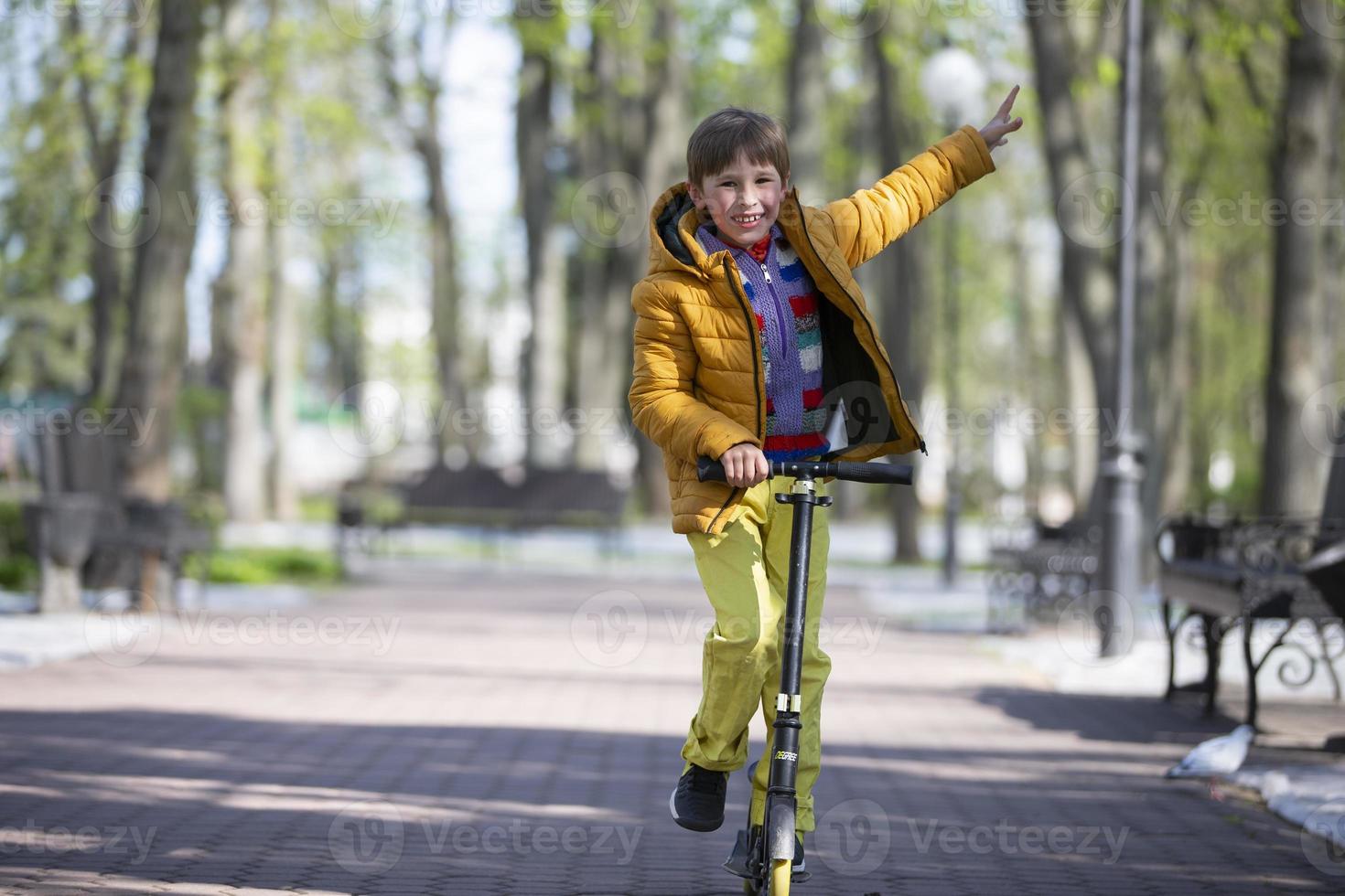 Happy boy on a scooter in the park. photo