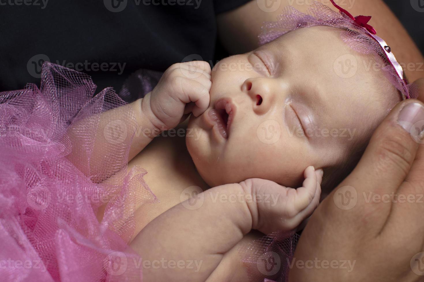 Newborn smart girl sleeps sweetly in her arms. photo