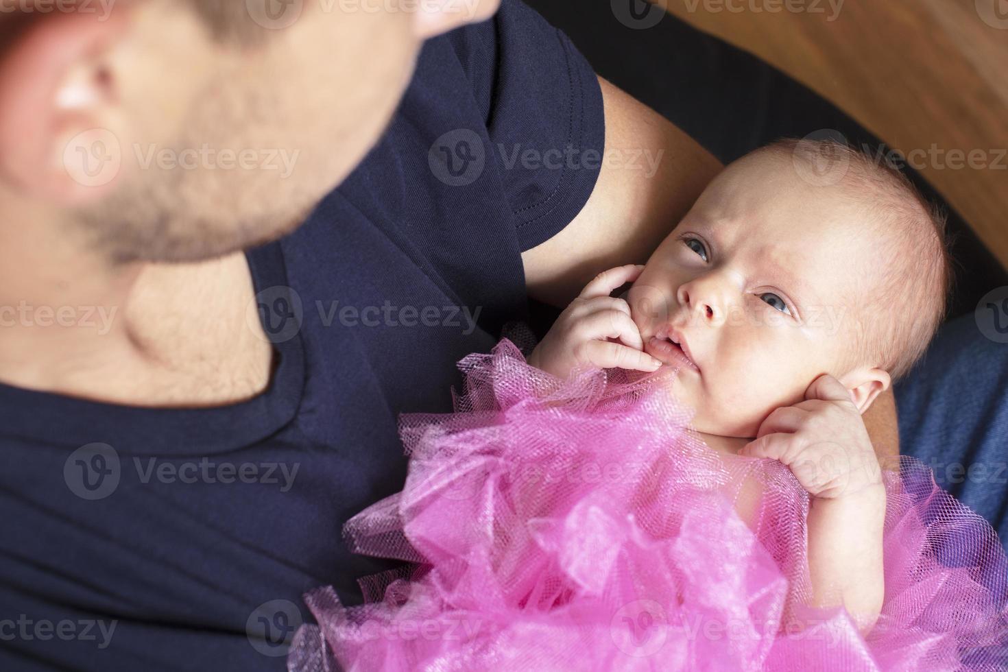 Newborn baby girl in the arms of her dad. photo