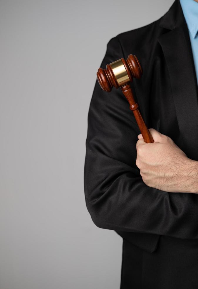 Law firm concept. Close up view of professional lawyer holding judge's hammer while standing against the grey wall. photo