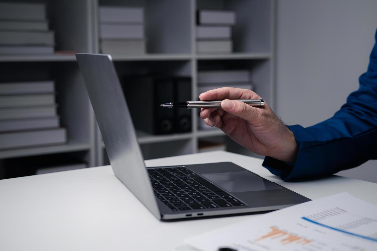 Close up view of businessman using laptop computer at office desk in the office room. photo