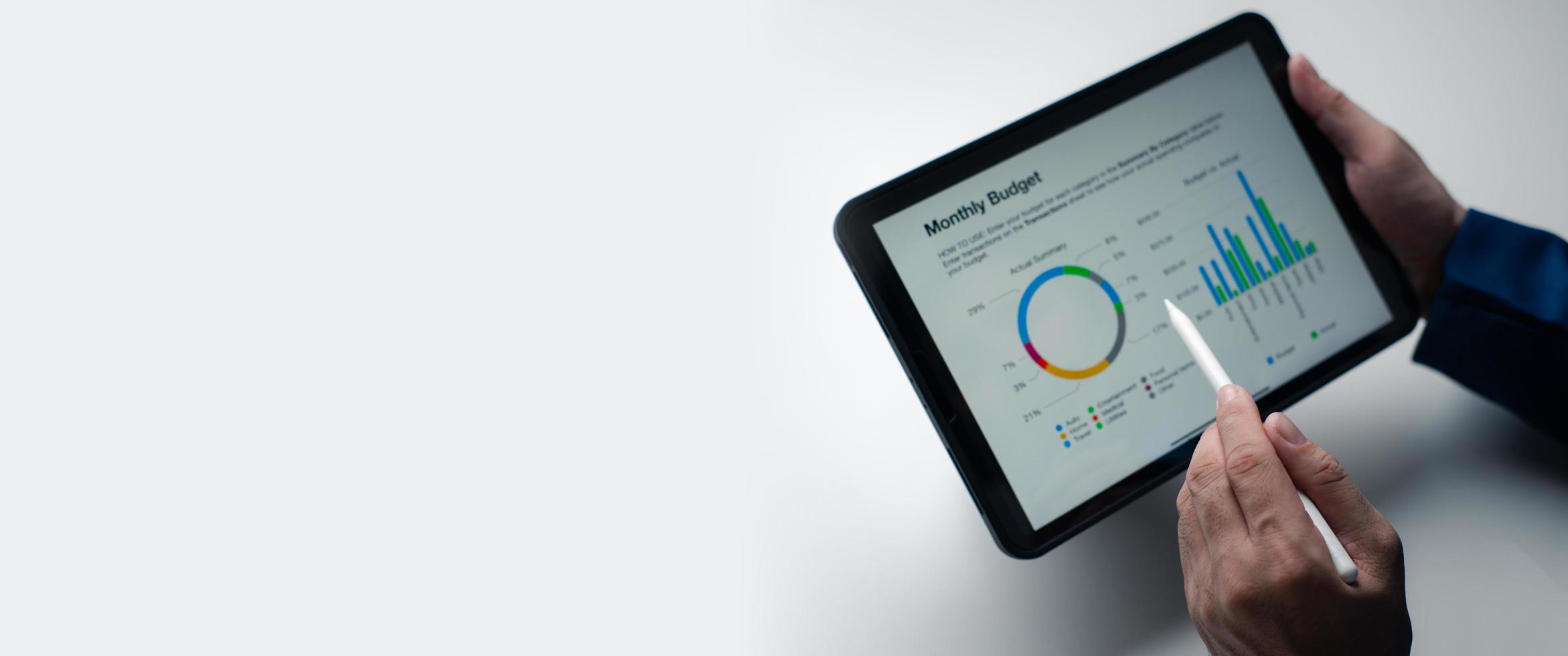 Close up view of young businessman using tablet to analyse the financial plan in the office room. photo