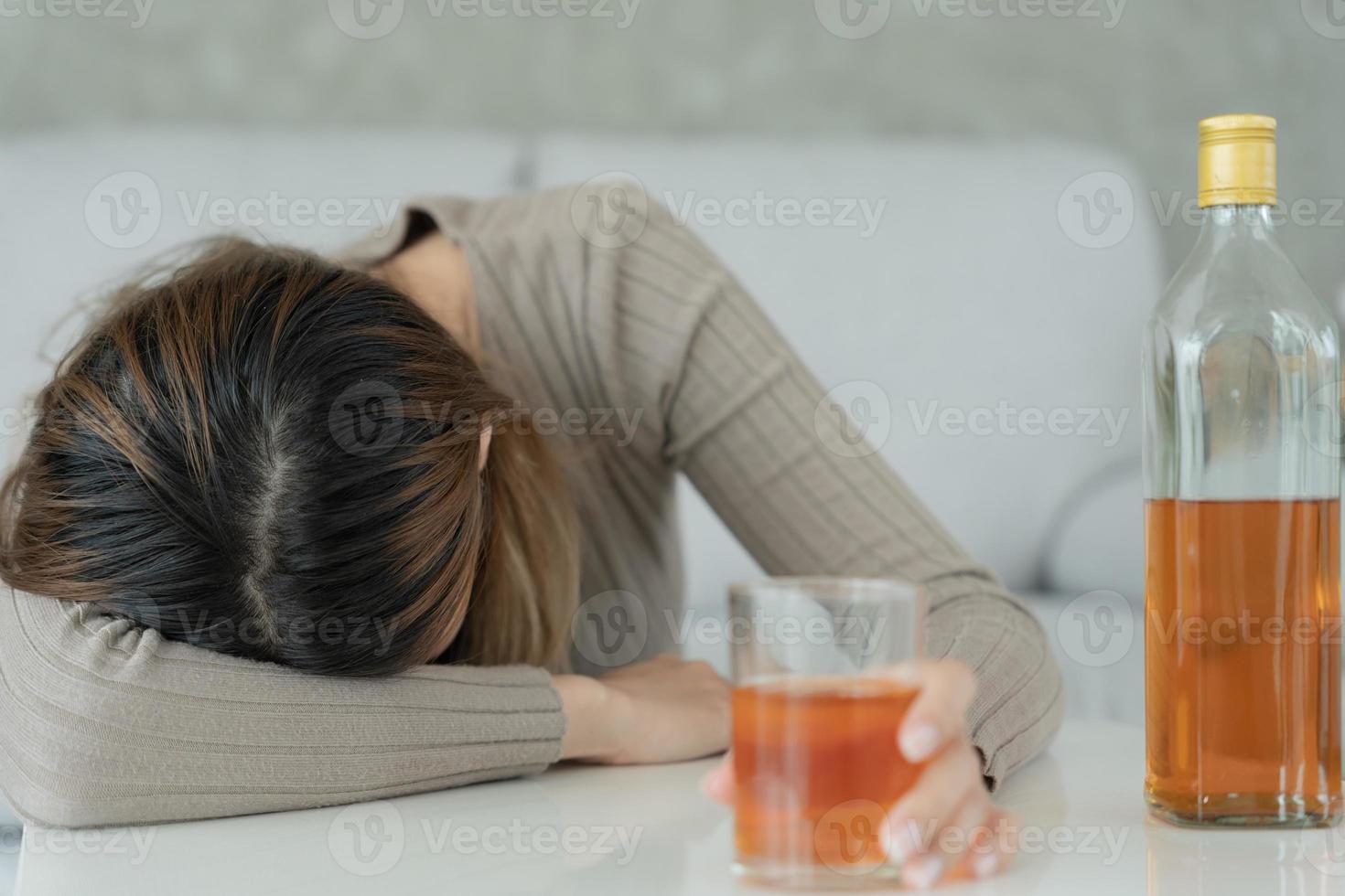 Depressed young Asian woman addicted feeling bad drinking whiskey alone at home, stressed frustrated lonely drinking alcohol suffers from problematic liquor, alcoholism, life and family problems photo