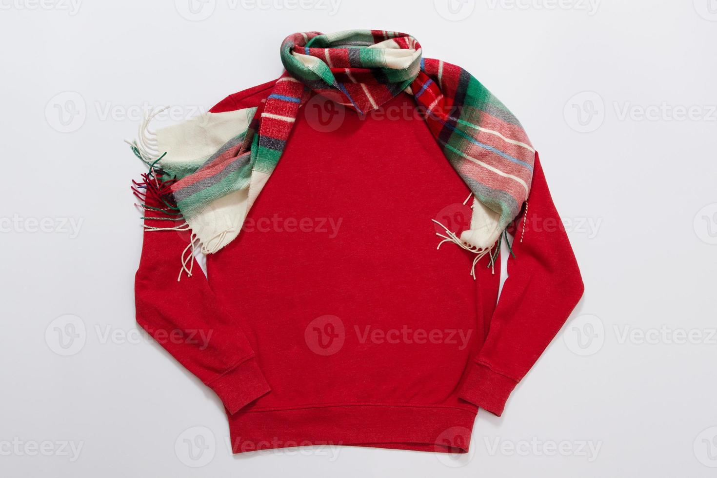 Close up red blank template sweatshirt with copy space and Christmas Holiday concept. Top view mockup hoodie and red holidays decorations on white background. Happy New Year accessories. Xmas outfit photo