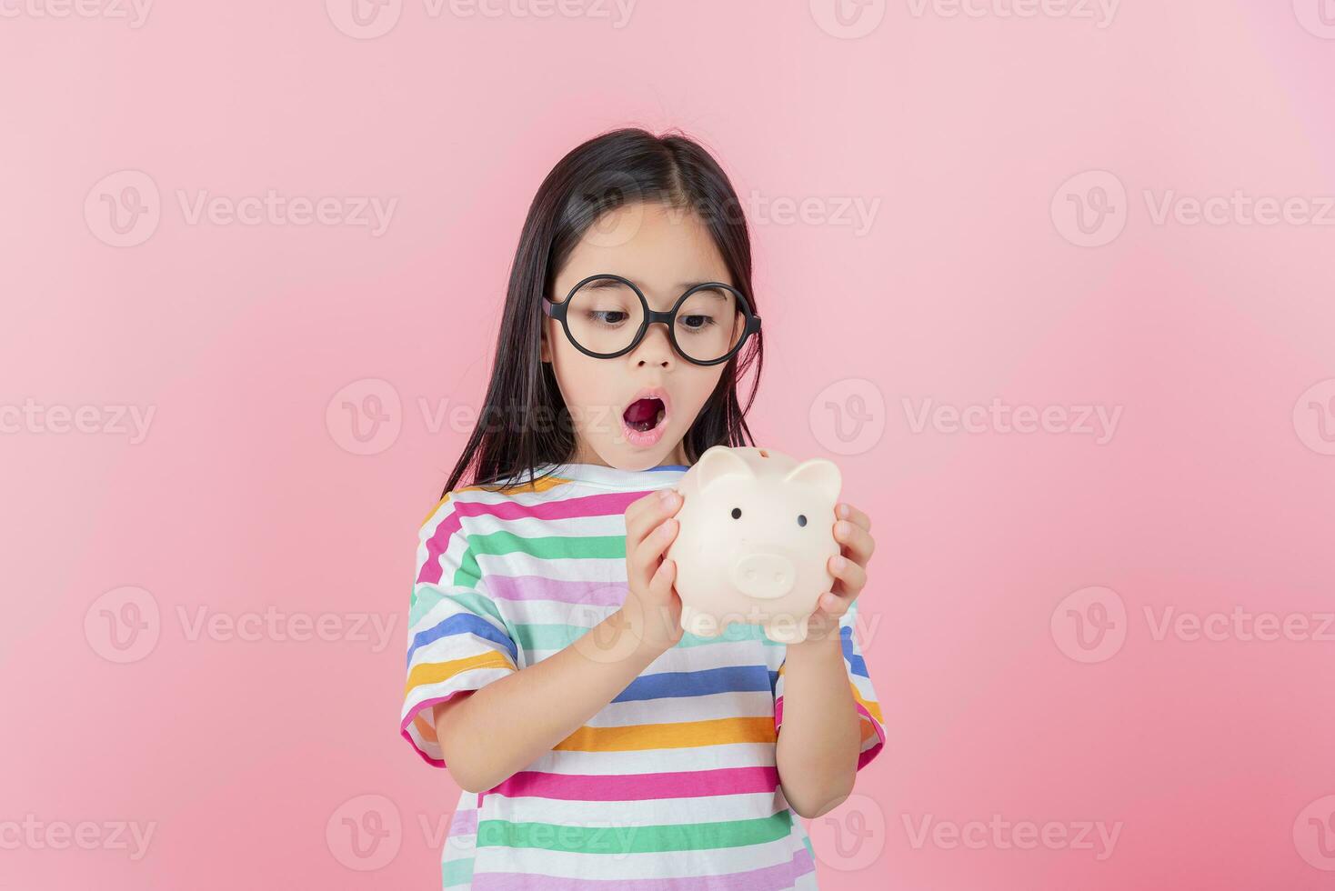 Little Asian girl saving money in a piggy bank, learning about saving, Kid save money for future education. Money, finances, insurance, and people concept photo