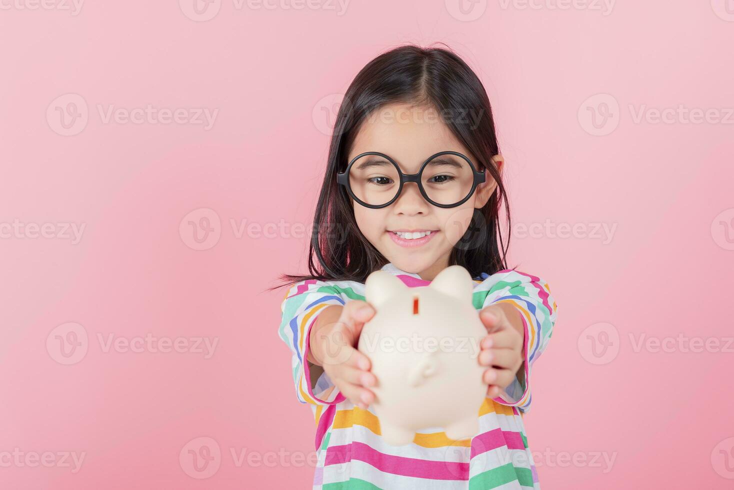 Little Asian girl saving money in a piggy bank, learning about saving, Kid save money for future education. Money, finances, insurance, and people concept photo