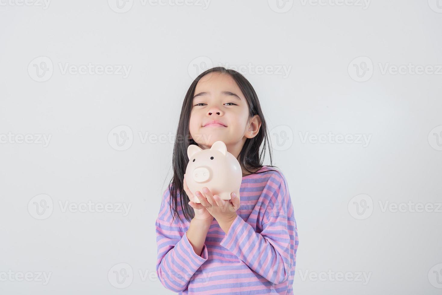 Little Asian girl saving money in a piggy bank, learning about saving, Kid save money for future education. Money, finances, insurance, and people concept photo