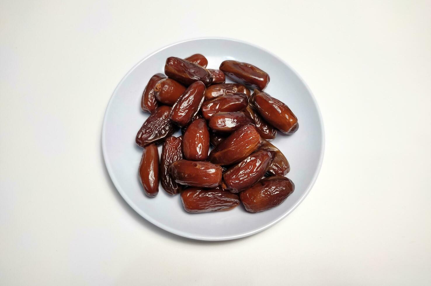 pile of dates on white mica plate, white background photo