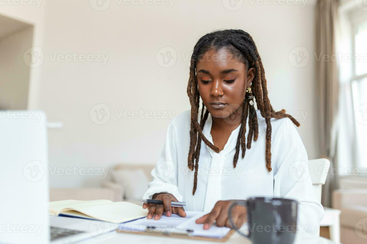 Remote job, technology and people concept - happy smiling young black business woman with laptop computer and papers working at home office photo