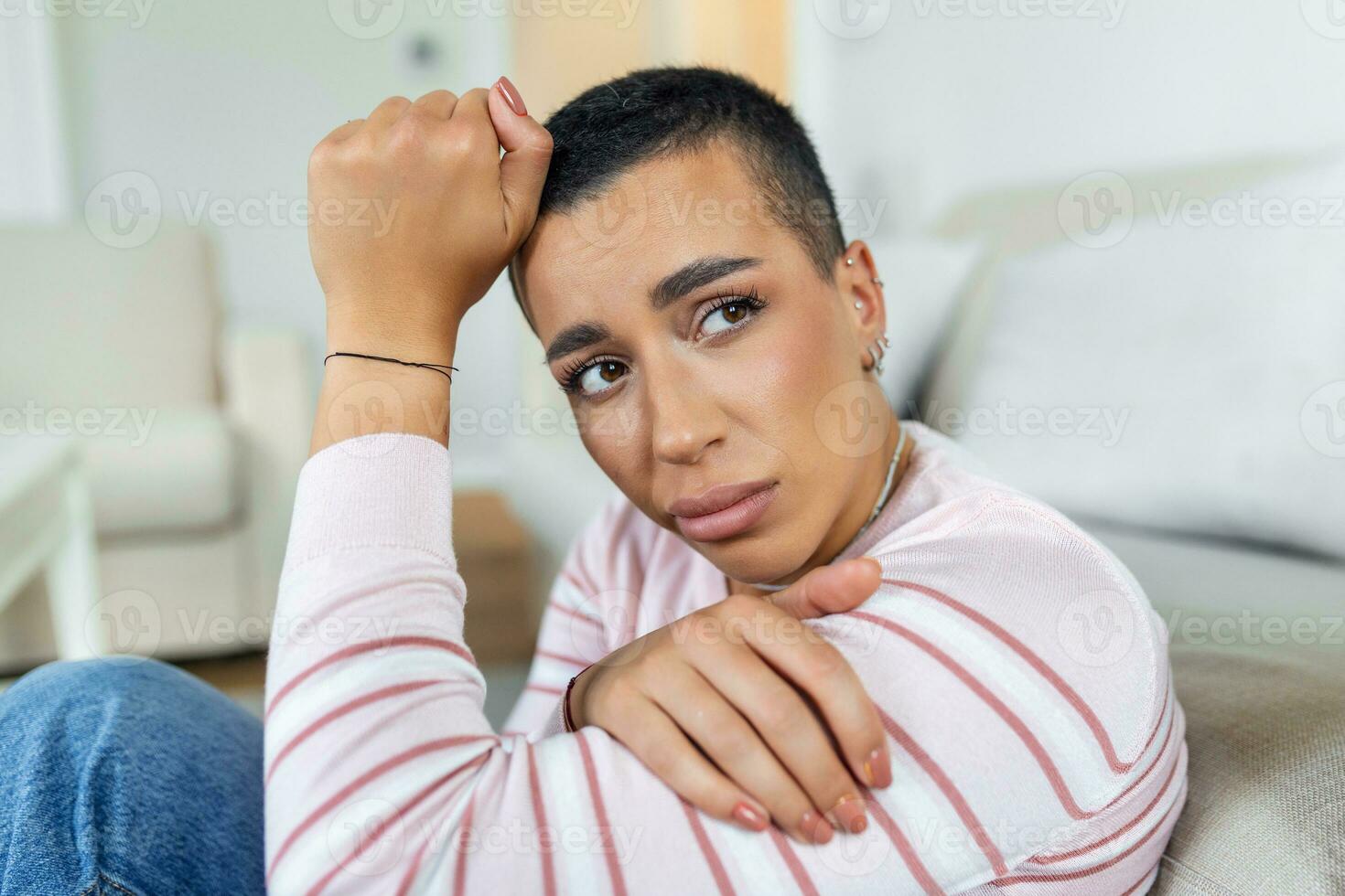 Unhappy african American woman on sofa crying. Lonely sad woman deep in thoughts sitting daydreaming or waiting for someone in the living room with a serious expression, sitting on couch photo