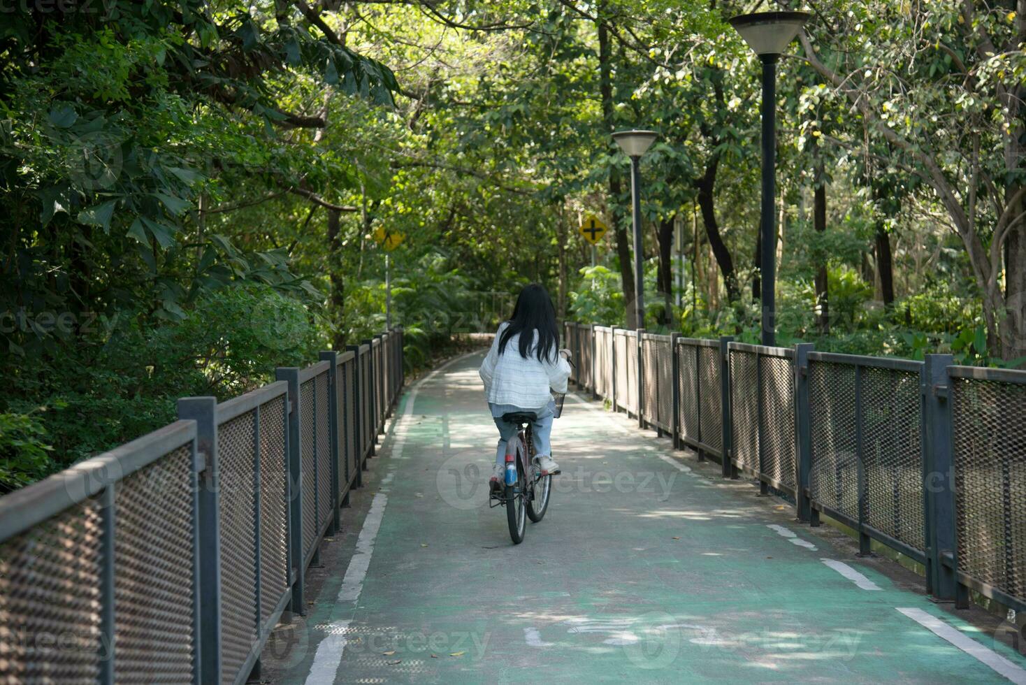asiático mujer montando un bicicleta en el parque. foto