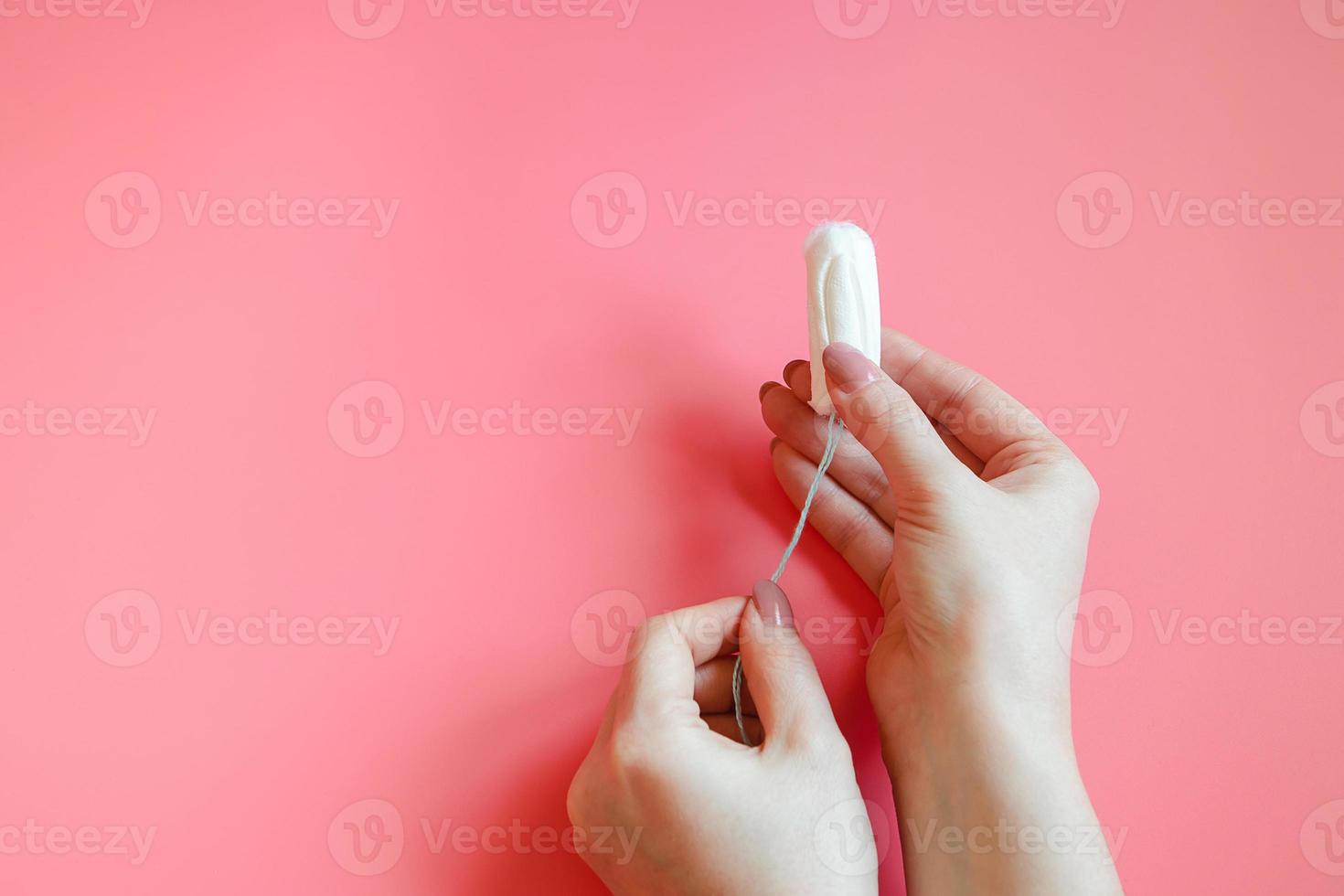 Woman is holding hygienic cotton tampon in her hands. photo