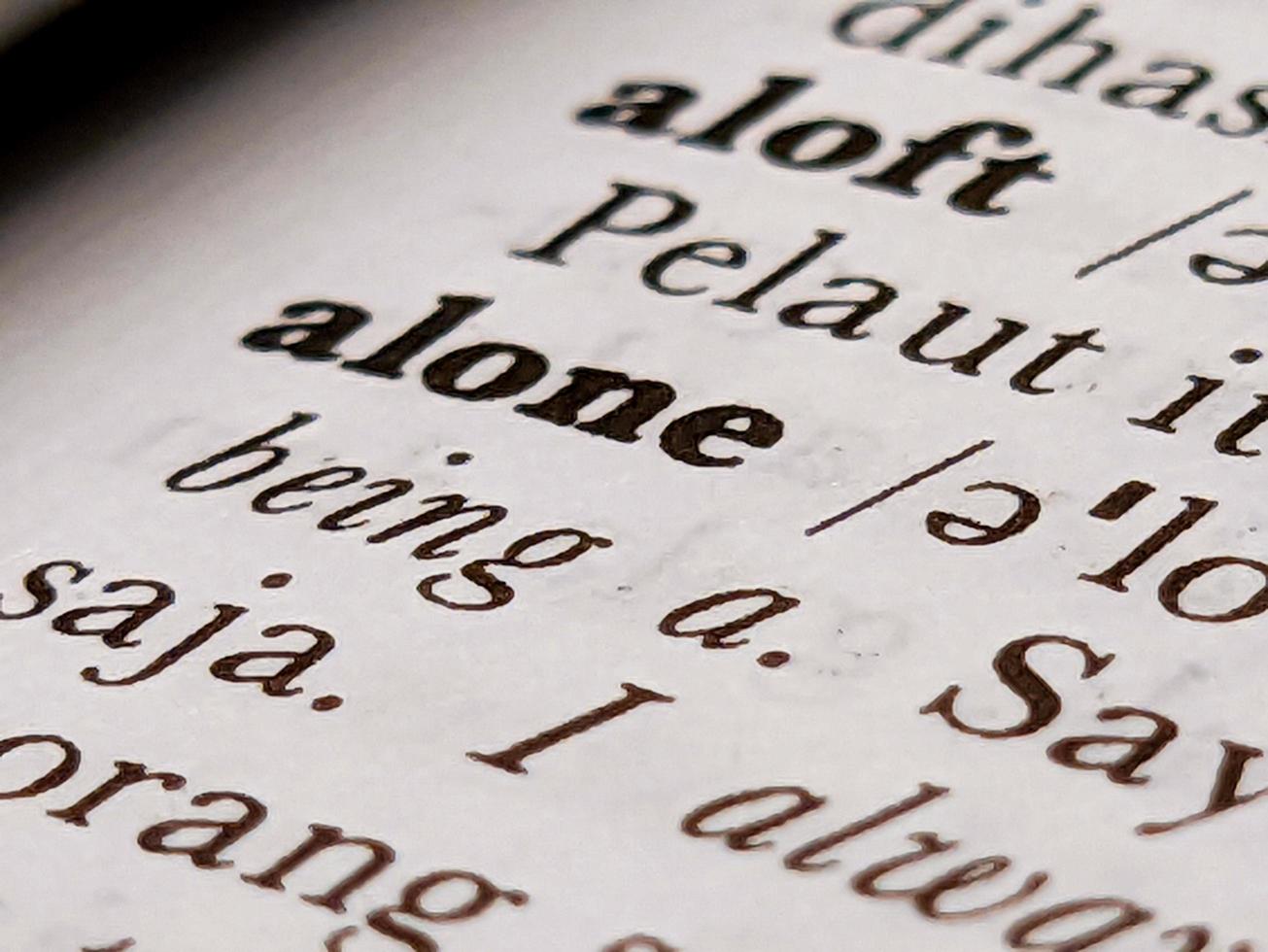 a close up of the word alone in the English to Indonesian dictionary. For word background or wallpaper photo