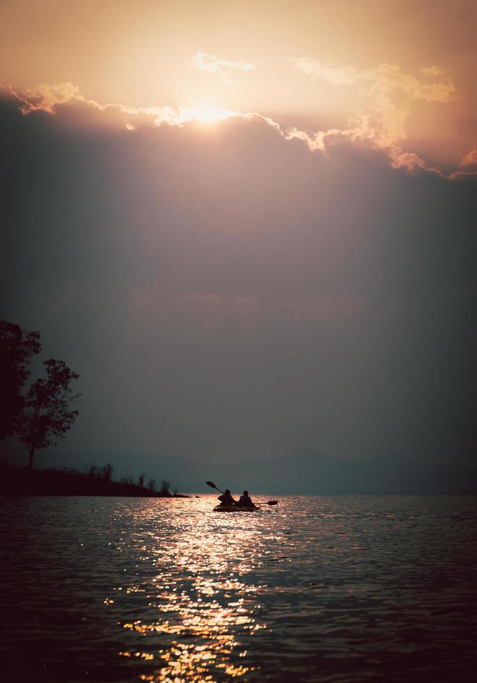 Silhouettes of people in kayak at sunset. photo