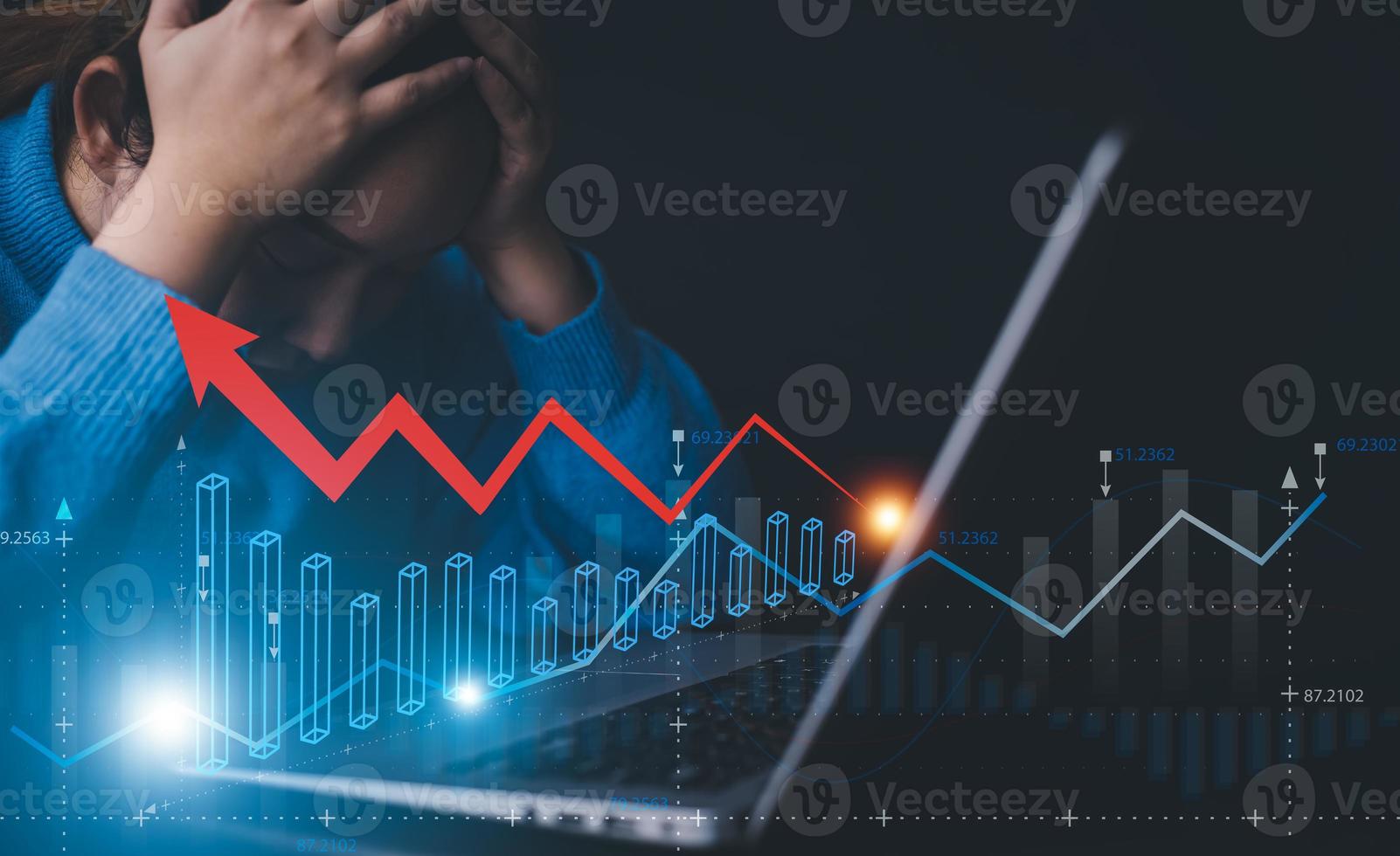 Businesswoman using a laptop and red arrow losses on the stock market chart concept, line market chart and Red arrows fall to the ground, indicating the economic recession that will occur in 2022-2023 photo