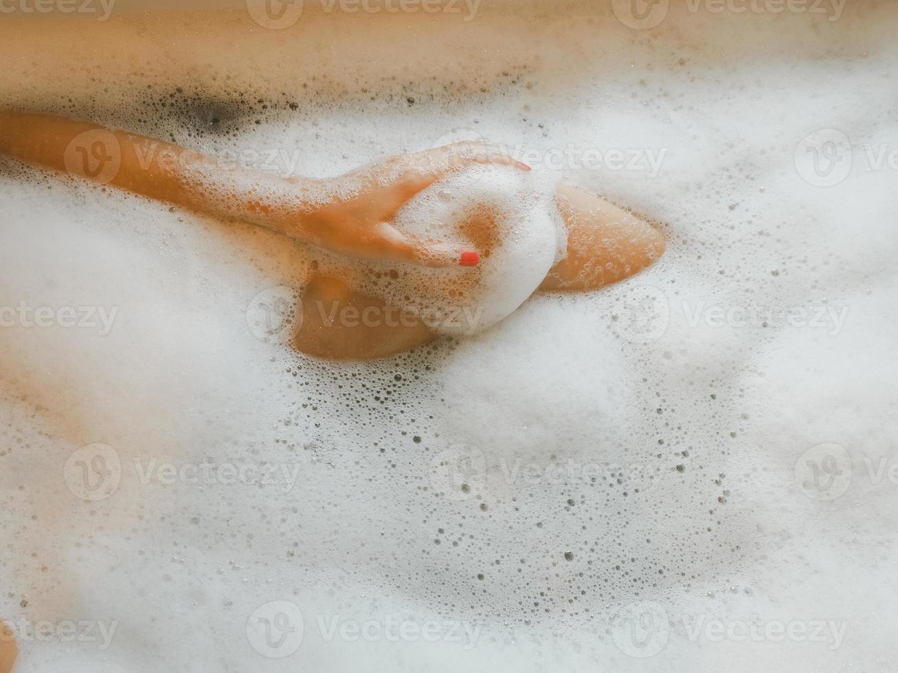 Female legs in bath foam who are enjoying and relaxing From infusion work to skin care spa photo