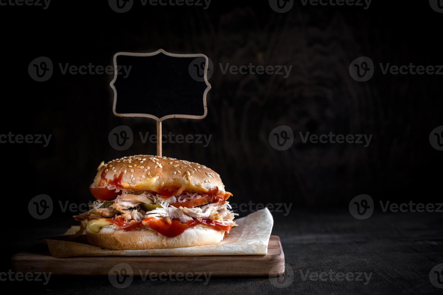 Chicken burger with sliced meat and chalkboard photo