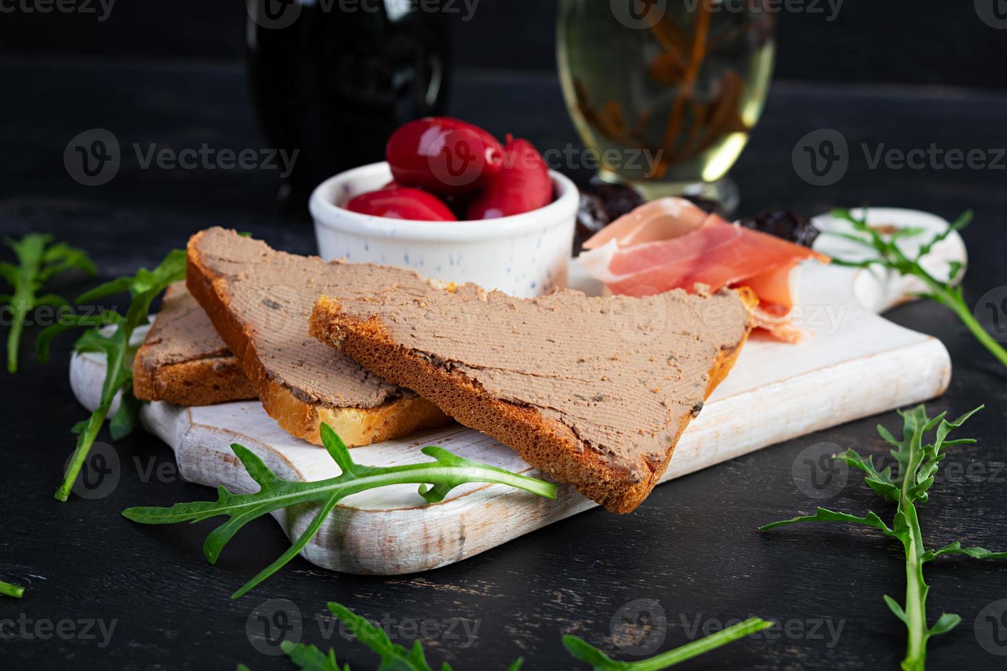 Grilled sandwich with pate with chicken liver and olives on dark background photo