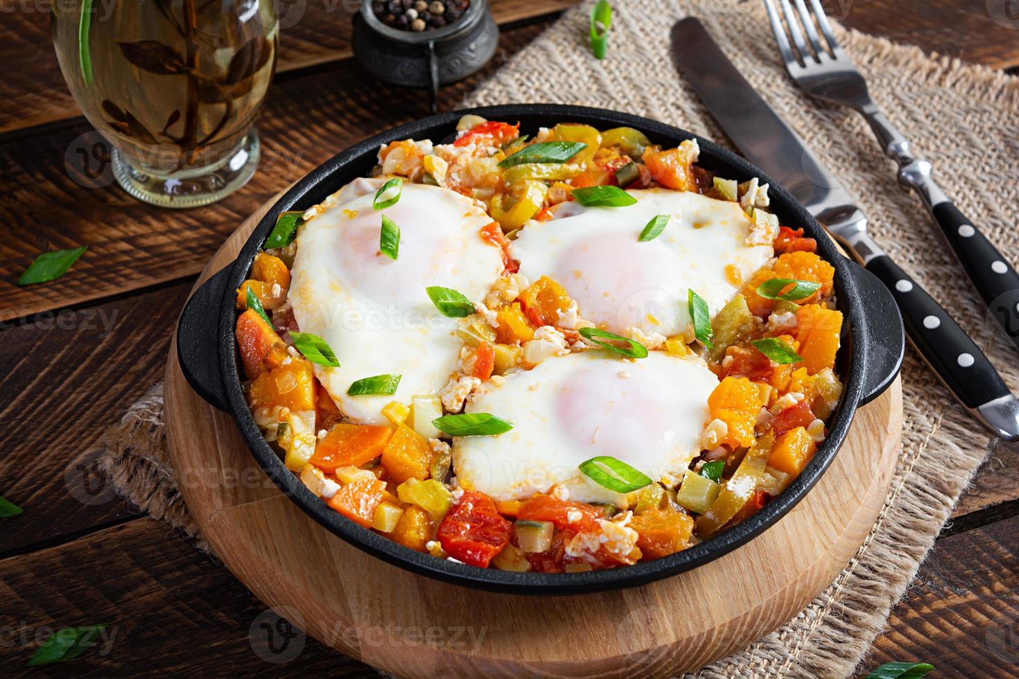 shakshouka en fritura cacerola. frito huevos con verduras, tomate, pimienta, calabaza y cebolla foto