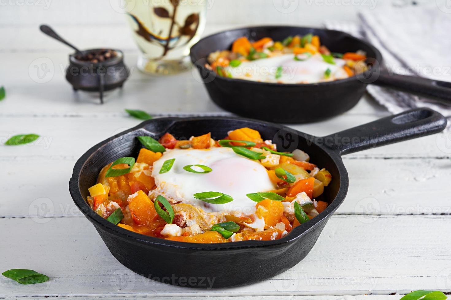 shakshouka en fritura cacerola. frito huevos con verduras, tomate, pimienta, calabaza y cebolla foto