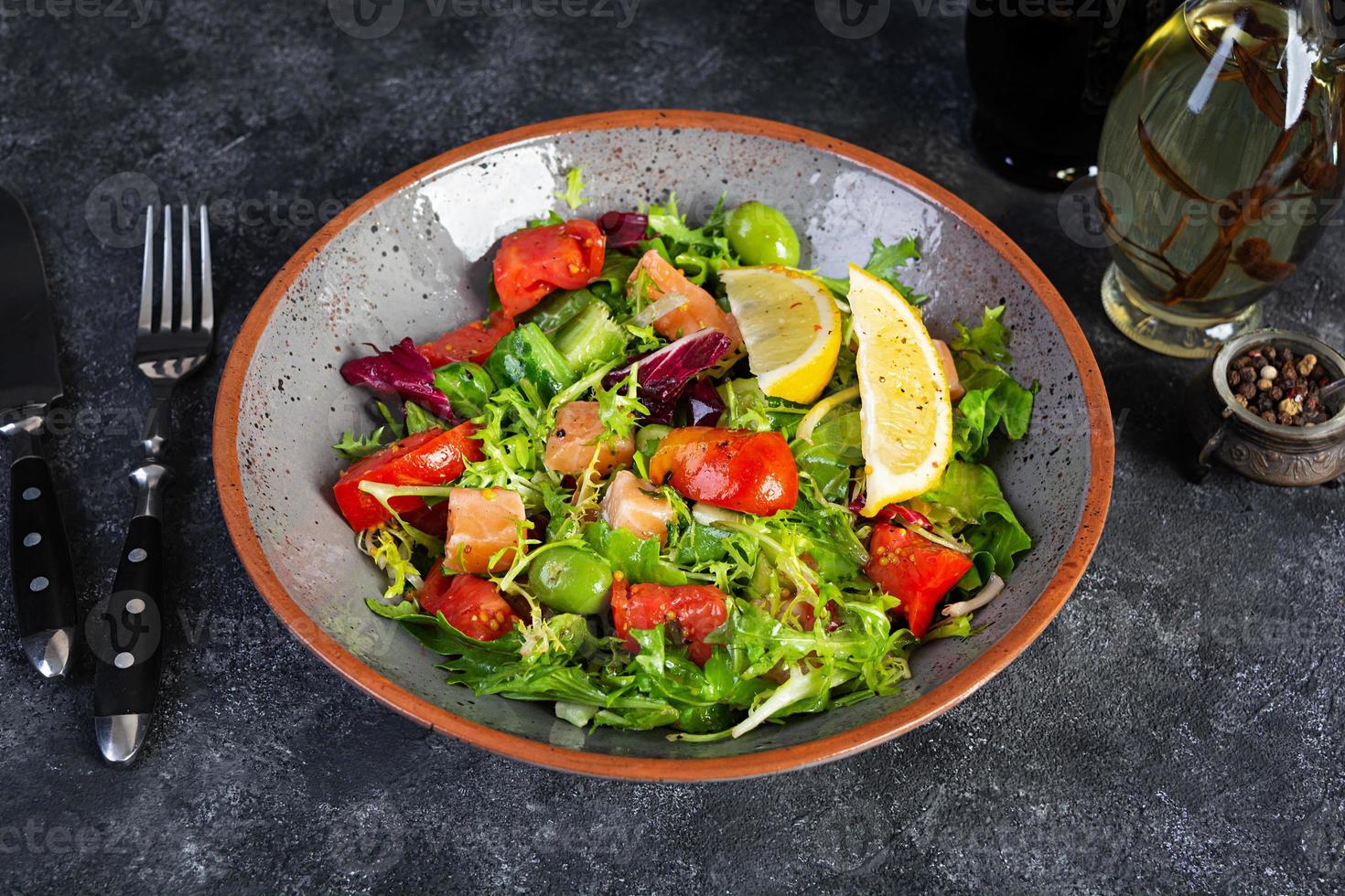 Fresh salad with salmon fish mixed with greens, tomato, olives, mustard and lemon juice photo