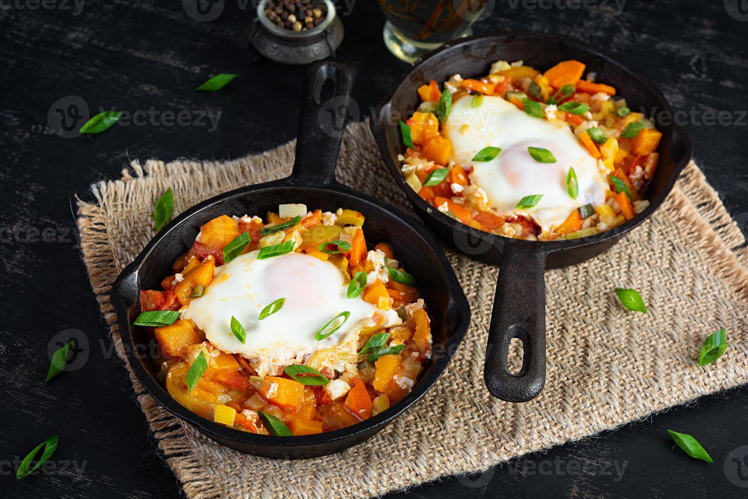 Shakshouka in frying pan. Fried eggs with vegetables, tomato, pepper, pumpkin and onion photo