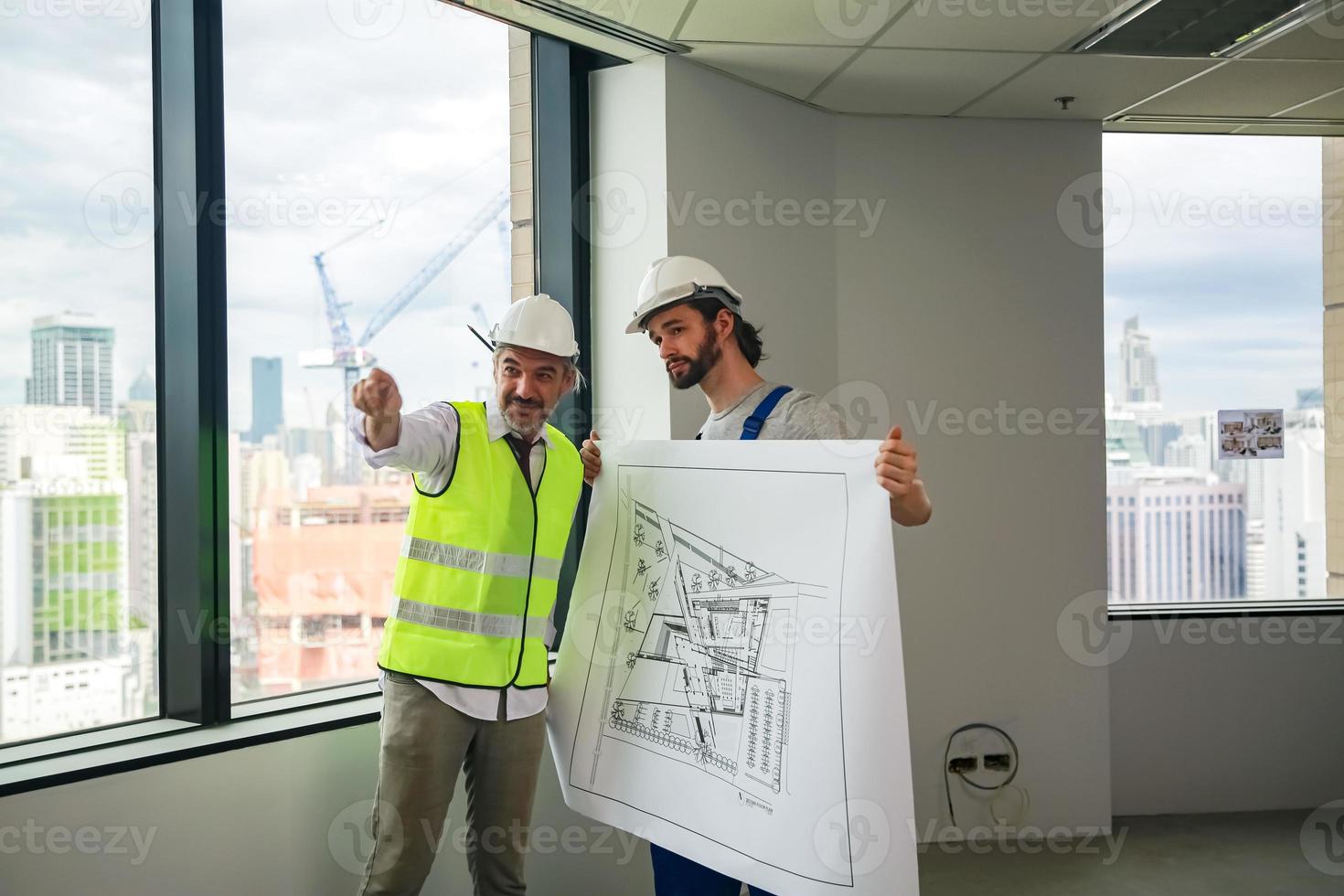 Man engineer standing on construction site, holding blueprints. photo