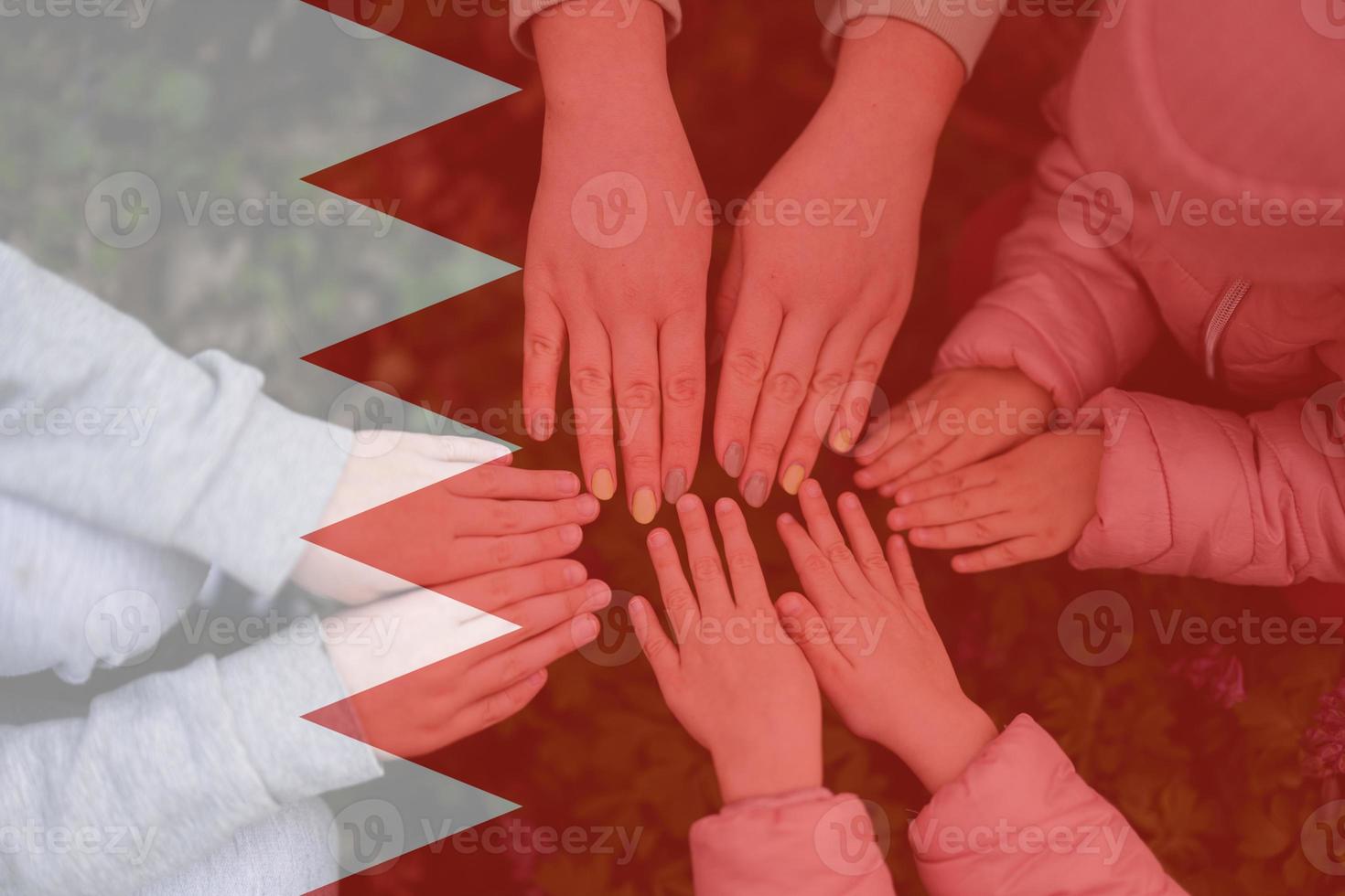 Hands of kids on background of Bahrain flag. Bahraini patriotism and unity concept. photo