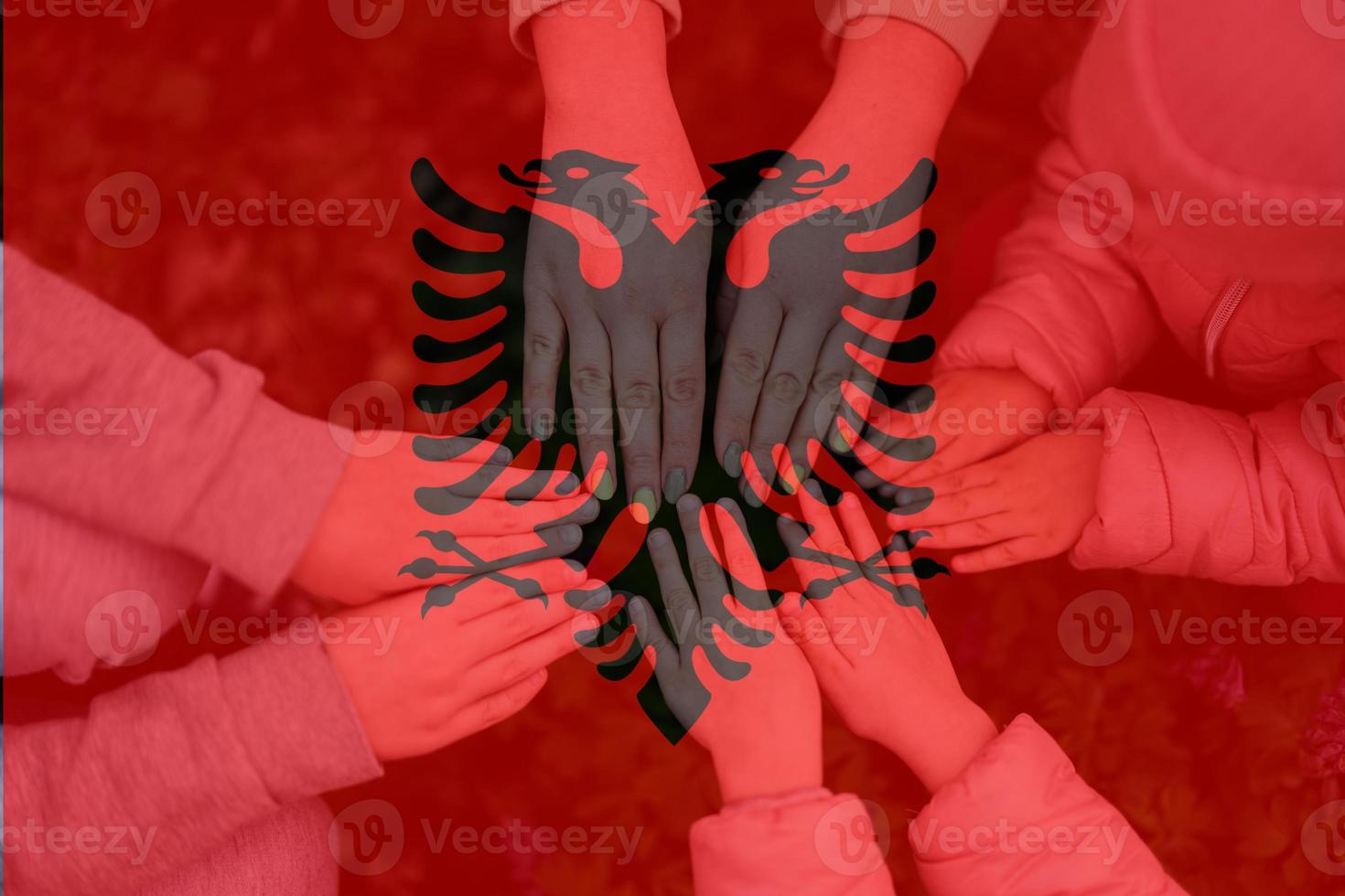 Hands of kids on background of Albania flag. Albanian patriotism and unity concept. photo