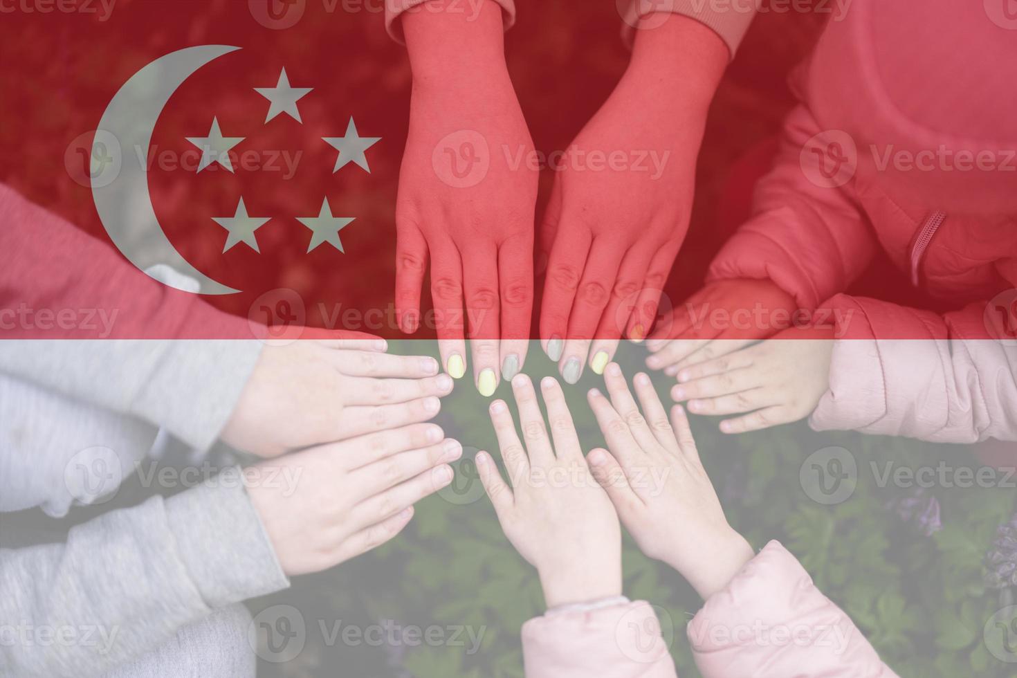 Hands of kids on background of Singapore flag. Singaporean patriotism and unity concept. photo
