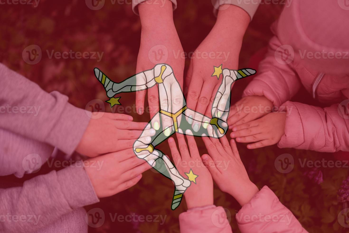 Hands of kids on background of Isle of Man flag. Manx patriotism and unity concept. photo