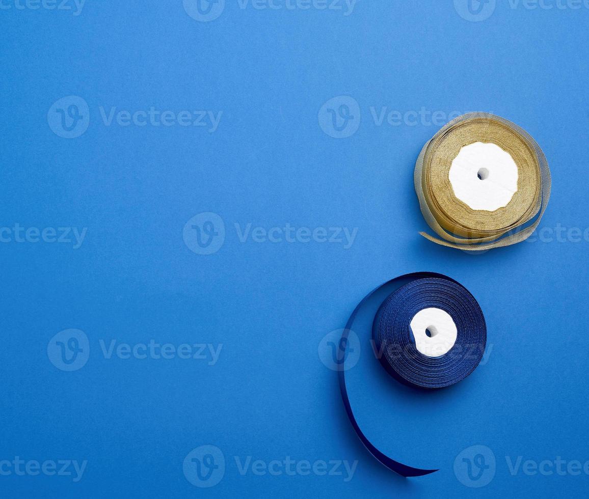 a roll of blue silk ribbon on a blue background, copy space photo