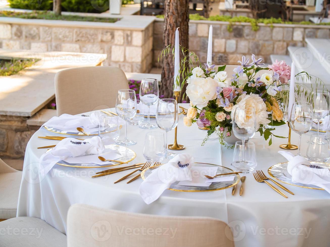 Table at luxury wedding reception event. Beautiful flowers on table and serving dishes and glasses and decoration photo