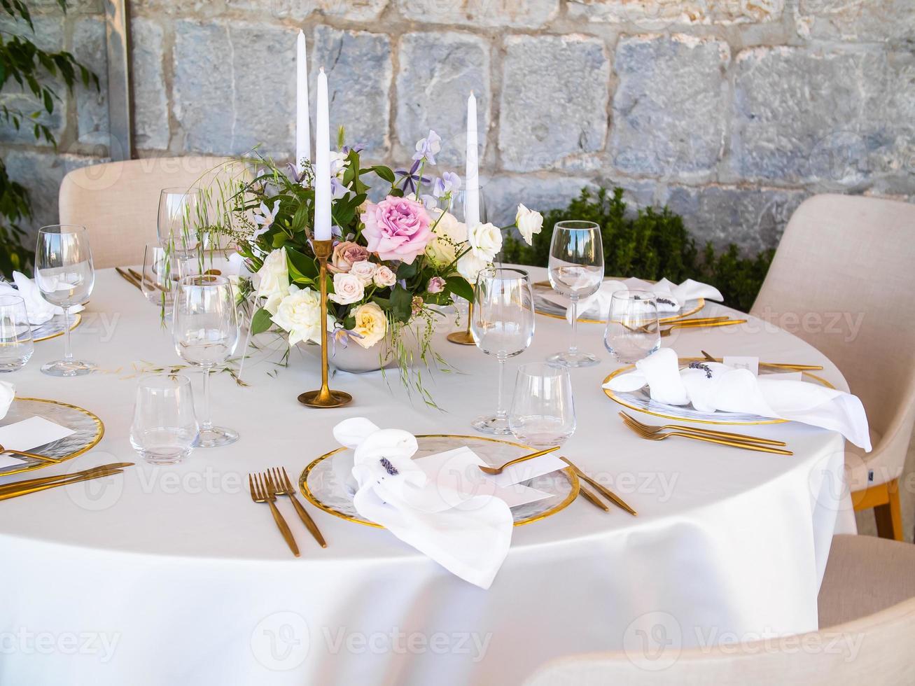 Wedding banquet concept. Chairs and round table for guests, served with cutler and, flowers and crockery and covered with a tablecloth photo