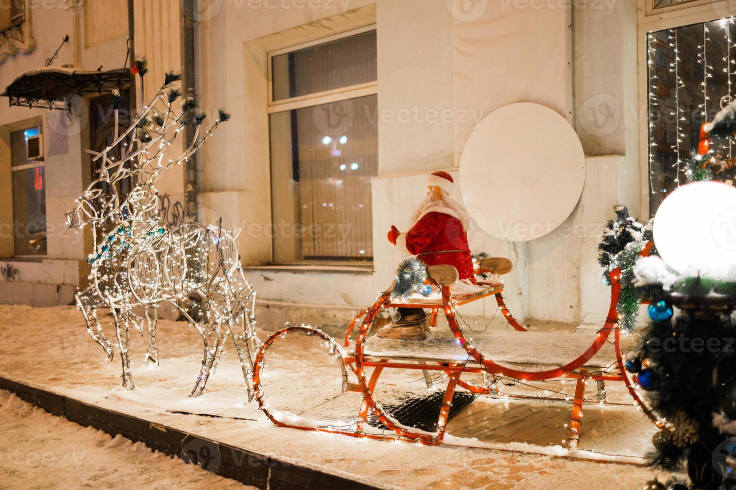 LEDs figure Santa Claus riding on sleigh during Christmas against restaurant or store in holiday winter city - festive and holidays season photo