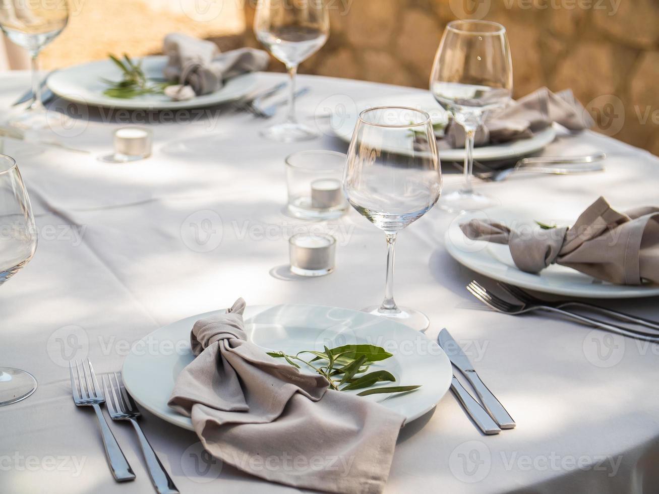 Boda banquete concepto. sillas y redondo mesa para huéspedes, servido con cuchillero y, flores y vajilla y cubierto con un Manteles foto