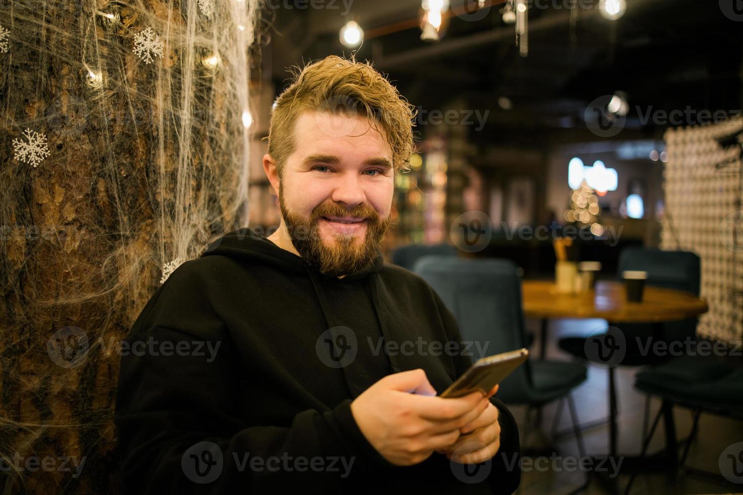 Portrait happy guy making money transaction via application on mobile phone with 4g internet sitting at cafe in street evening, serious millennial man reading text message on smartphone photo