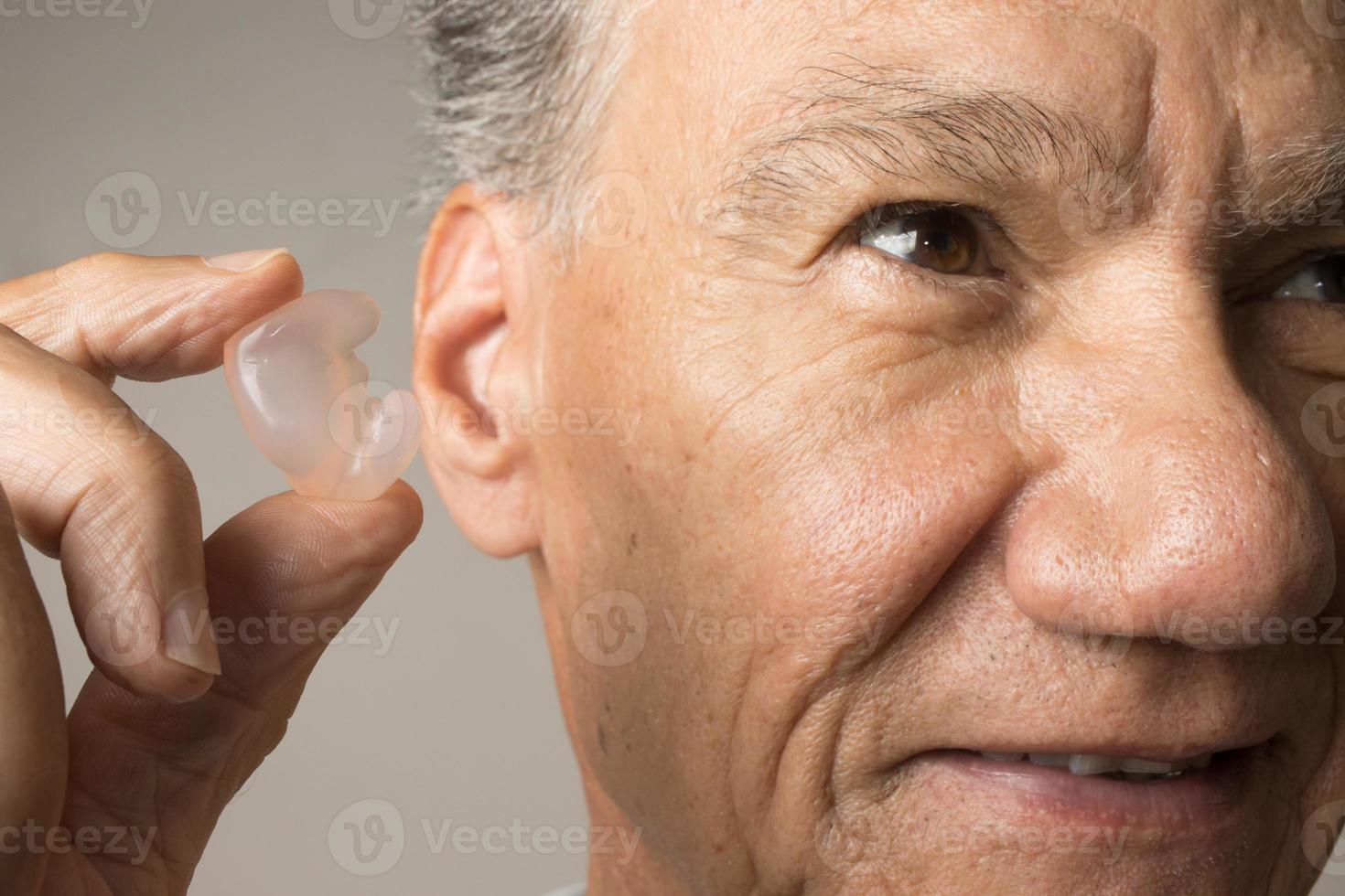 Older Man using custom made silicone earplugs for hearing protection photo