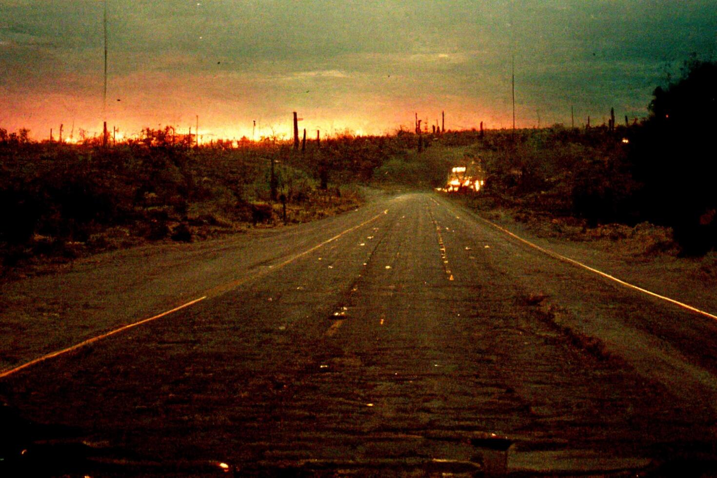 car driving down the middle of a dirt road. . photo