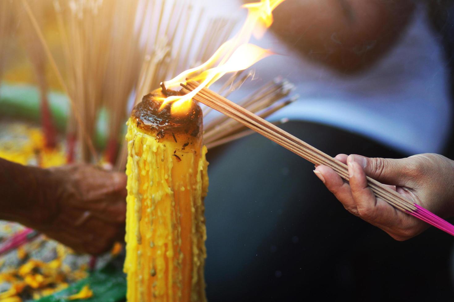 Holding incense into candle light for belief and Worship the gods of Buddhism and Hinduism in temple at Thailand photo