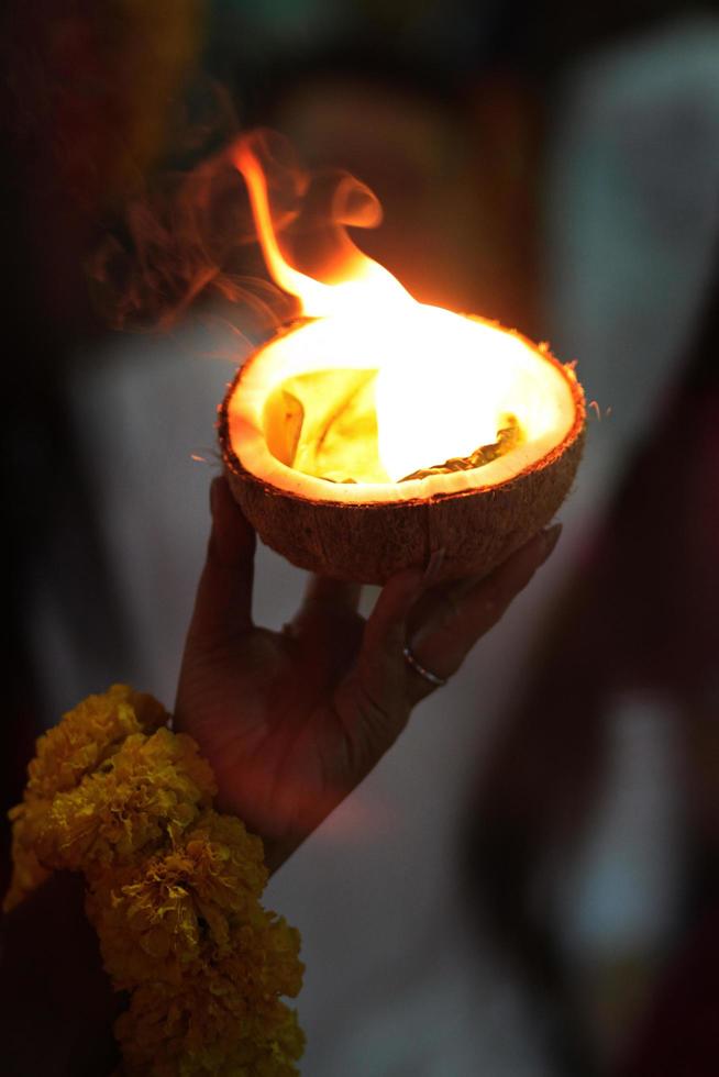 mujer mano participación ligero un fuego en un Coco Shel para creencia y Adoración el Dioses de hinduismo en Tailandia foto