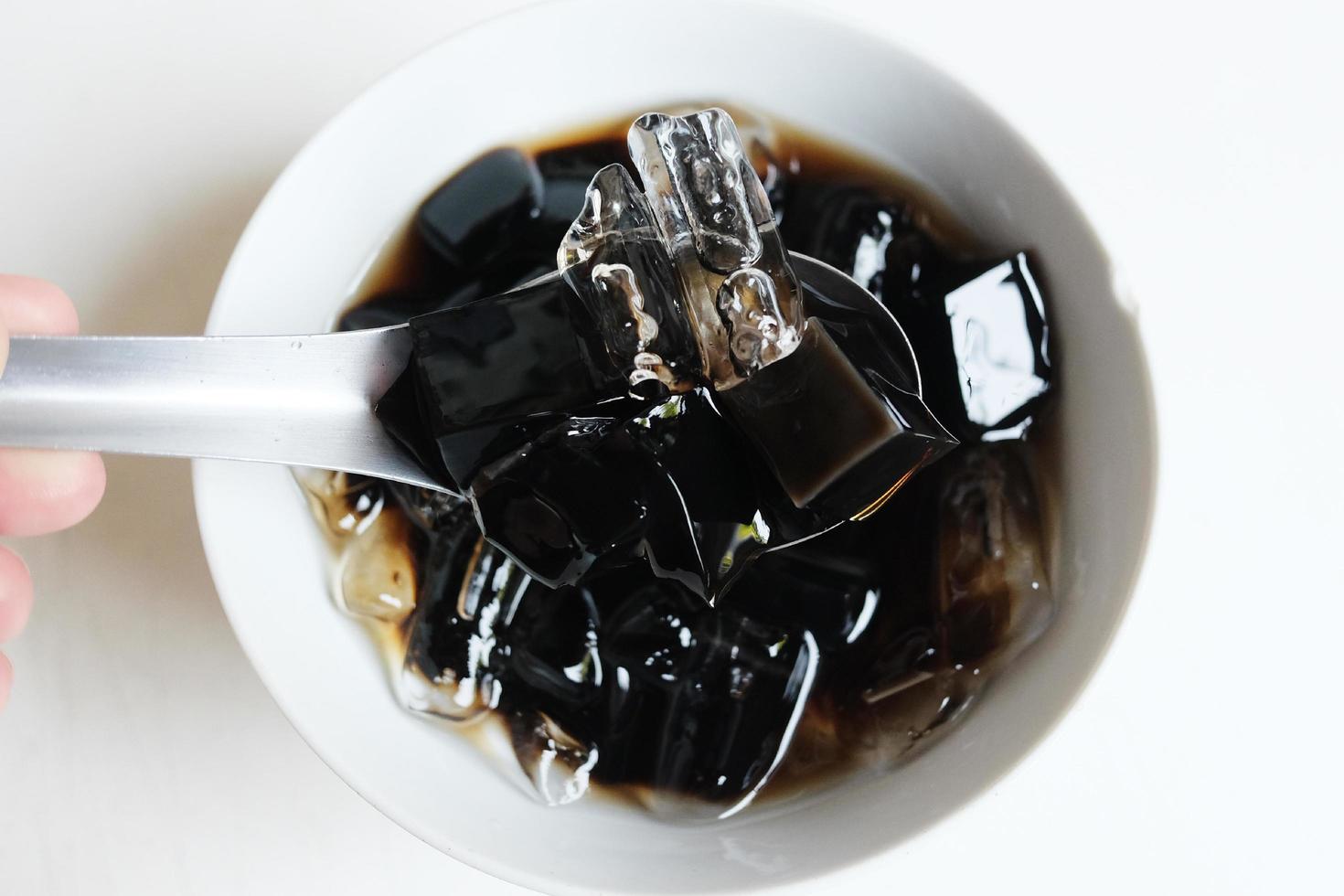 Thai Sweet dessert grass jelly with Ice in white bowl. A kind of Chinese vegetable is black jelly or Herbs can relieve heat in human body system and Aphthous stomatitis in summertime. photo
