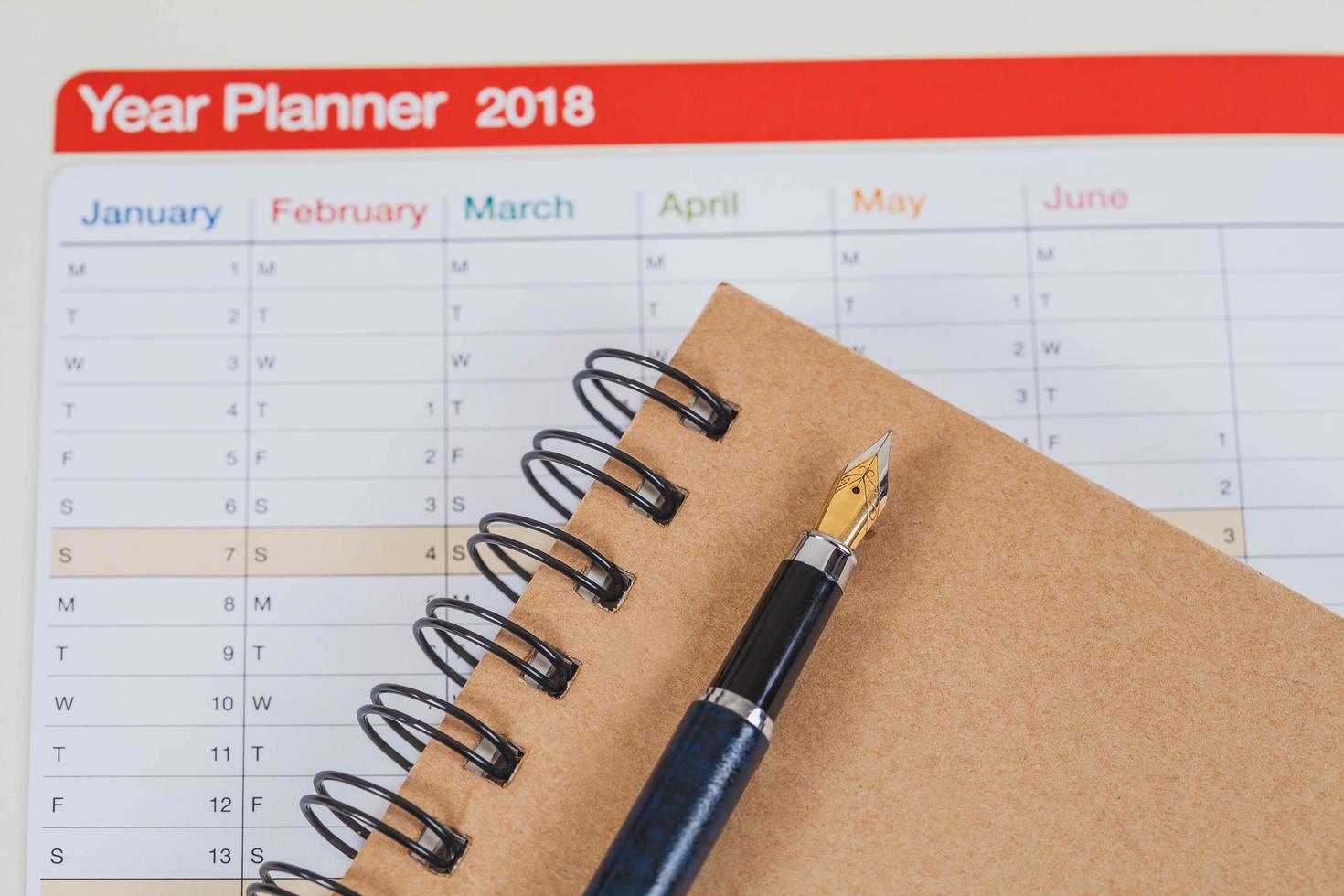 personal organizer or planner with fountain pen on wood table. photo