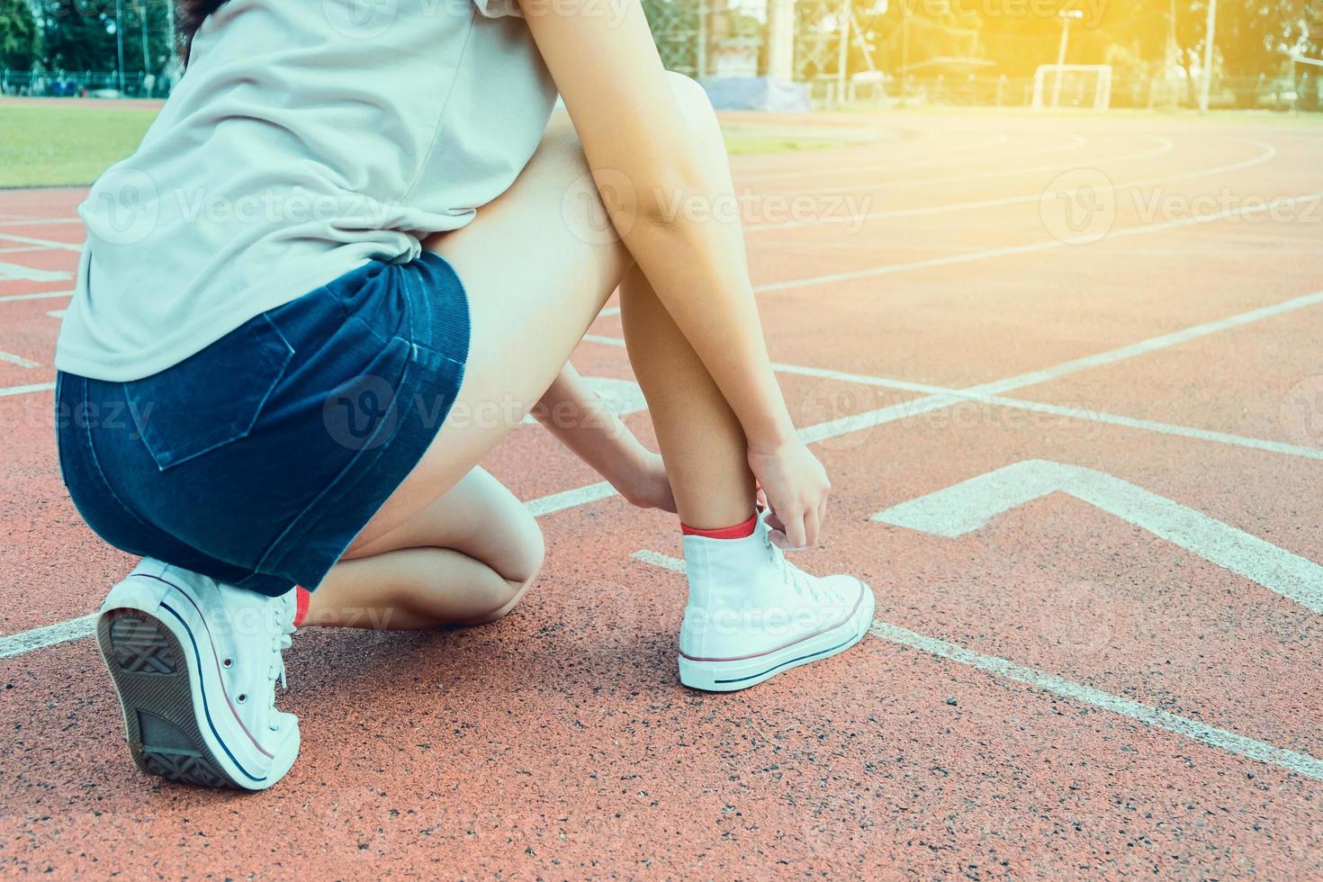 Woman runner tying shoelace on running racetrack photo