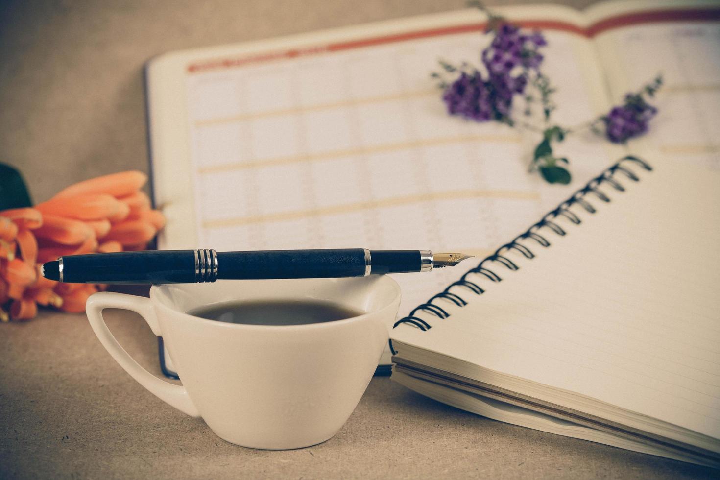 personal organizer or planner with fountain pen and hot coffee on wood table. photo