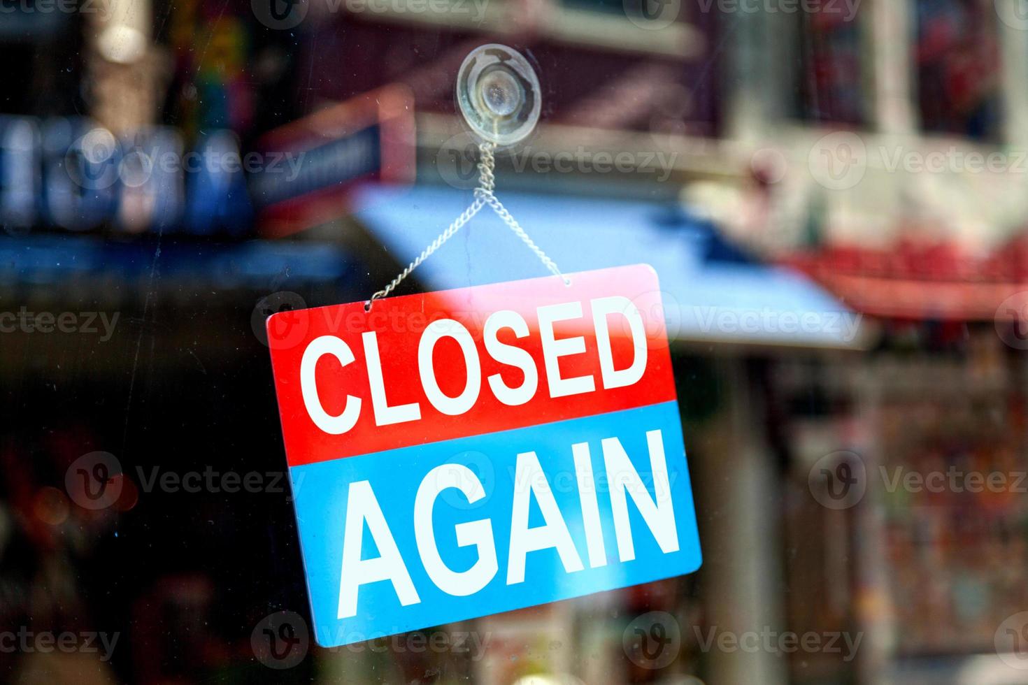 Closed again sign in a store window photo