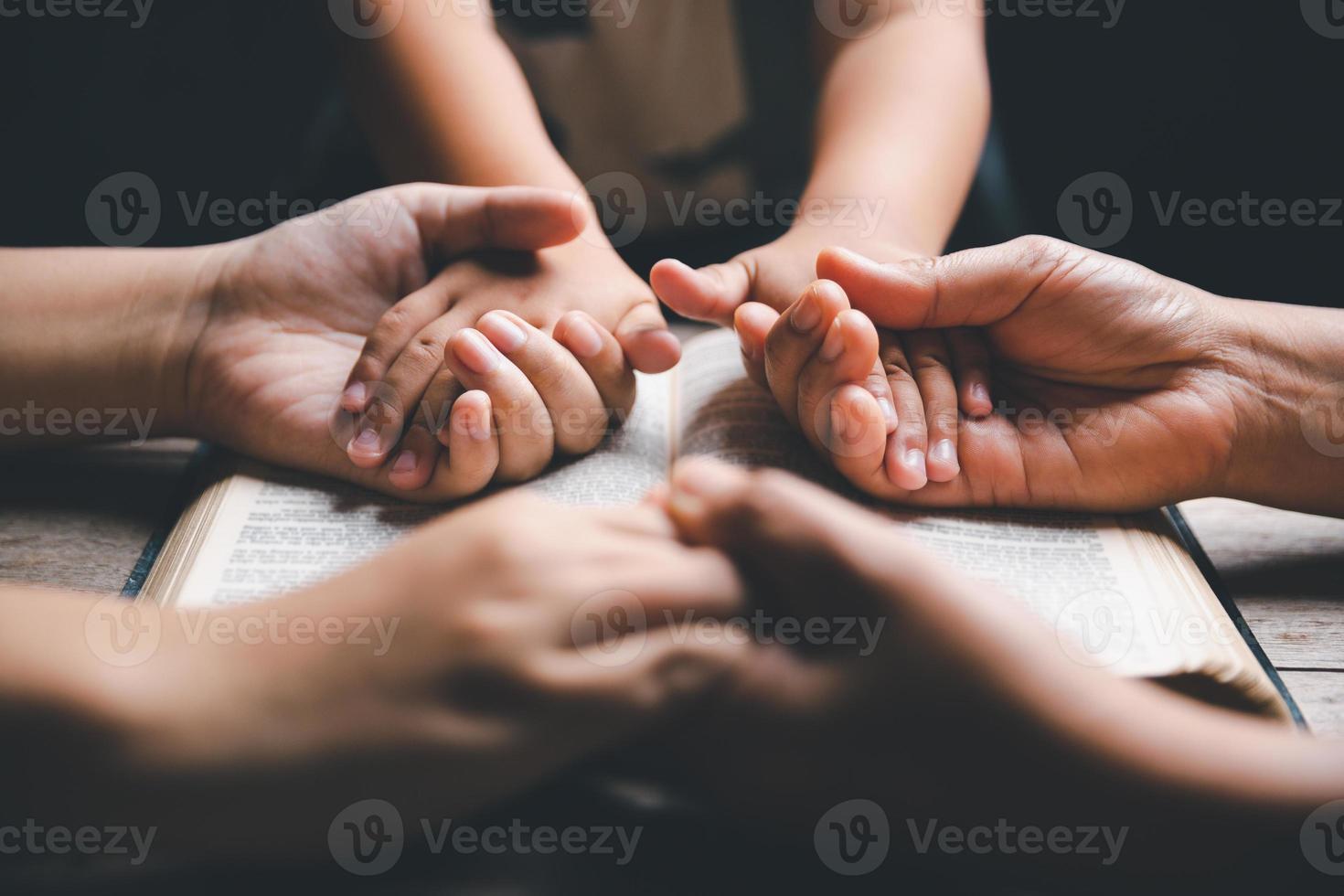 Christian family praying together concept. Child and mother worship God in home. Woman and boy hands praying to god with the bible begging for forgiveness and believe in goodness. photo