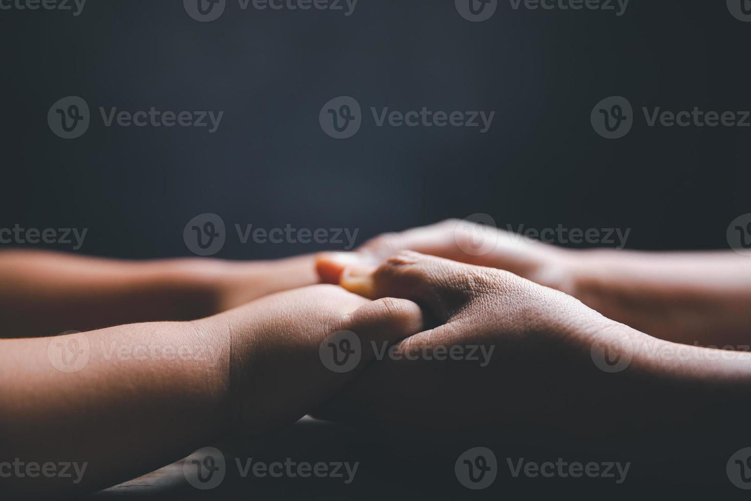 Christian family praying together concept. Child and mother worship God in home. Woman and boy hands praying to god with the bible begging for forgiveness and believe in goodness. photo